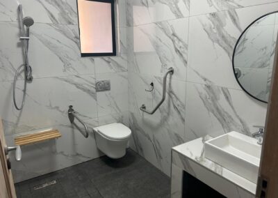 An accessible bathroom with a walk-in shower, grab rails and a fold-down seat
