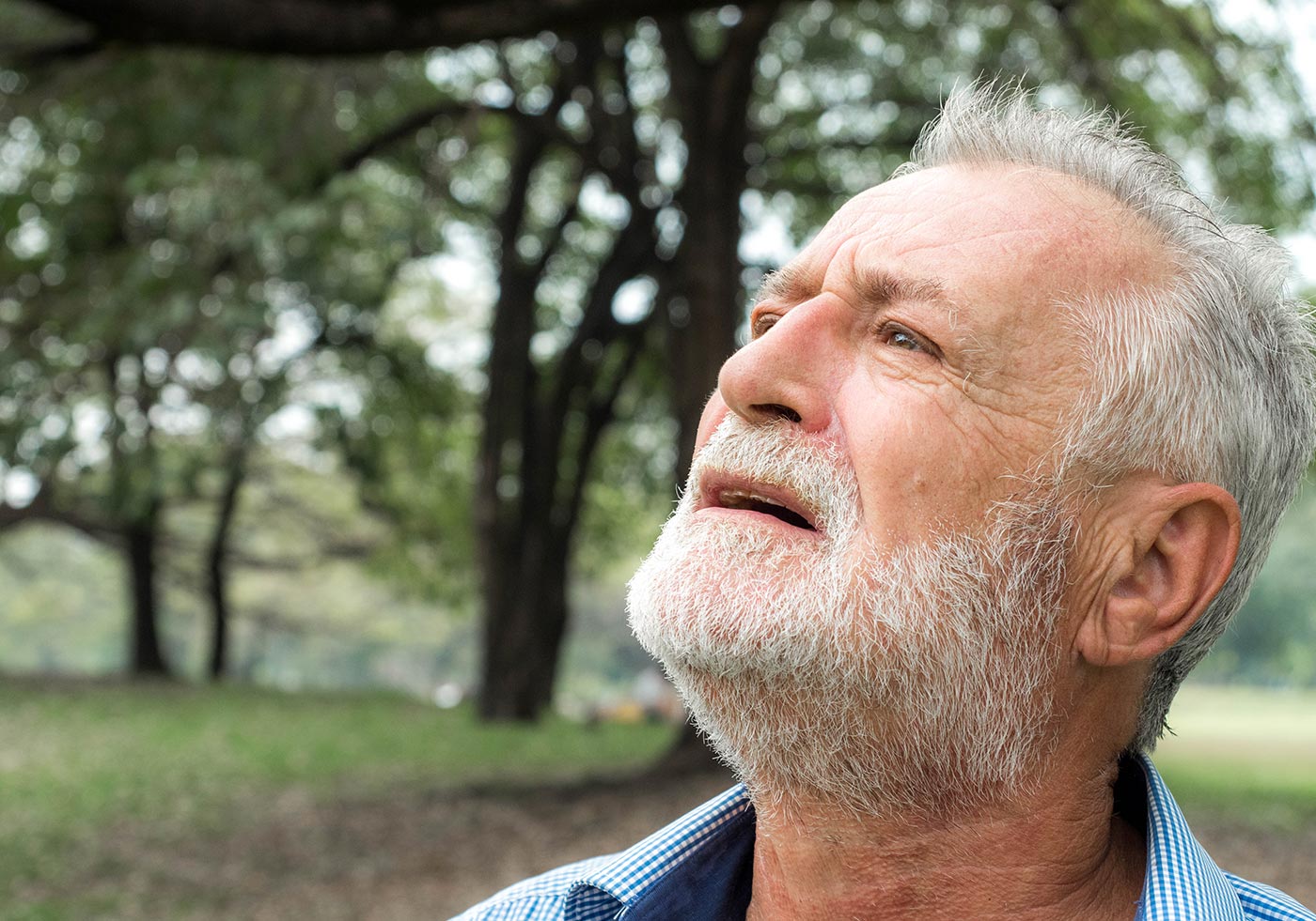An older man standing outdoors, looking into the distance
