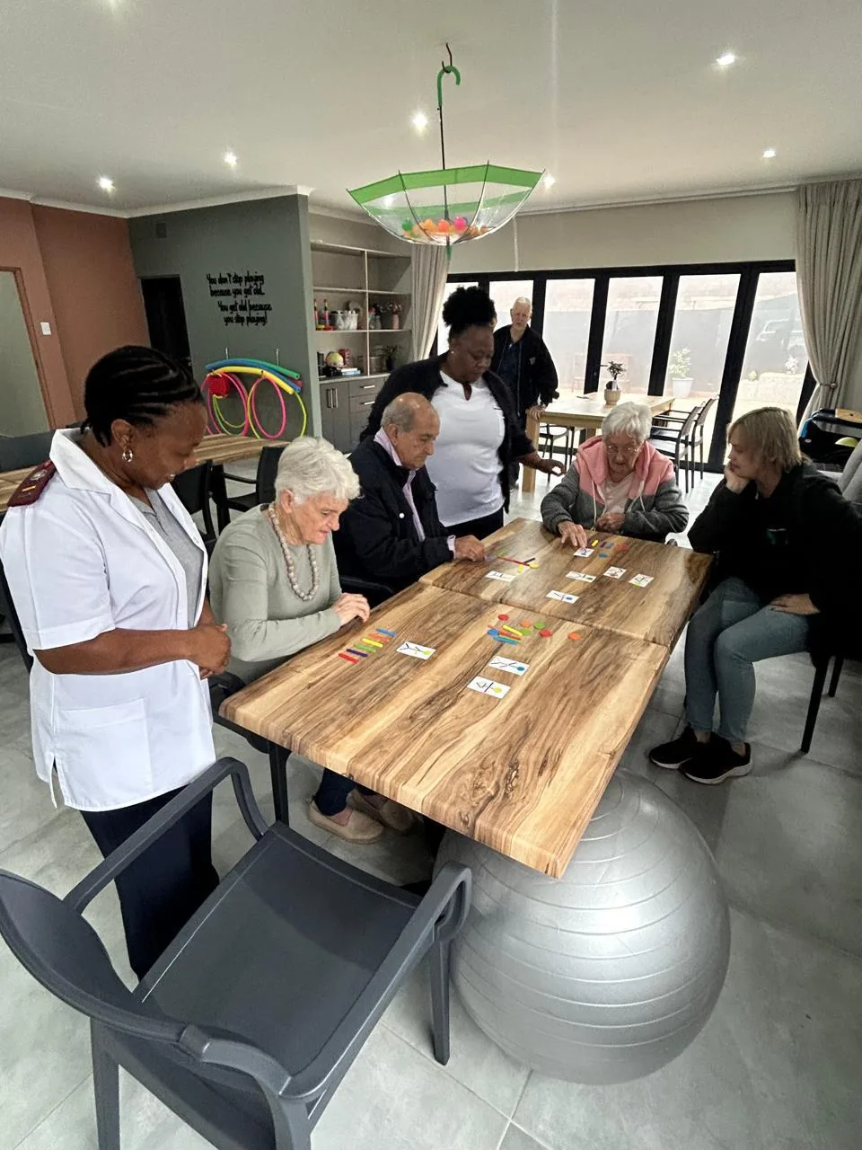 A nurse sitting with residents at the communal table A nurse sitting with residents at the communal table